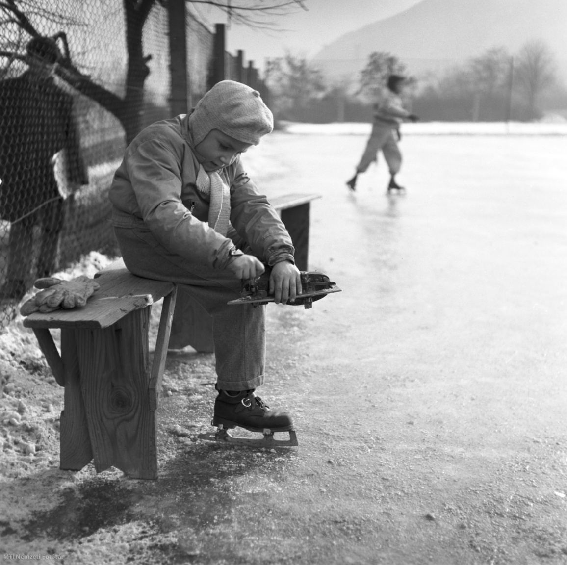 Felcsatolja a korcsolyáját egy kisfiú egy budapesti jégpályán 1958. december 10-én