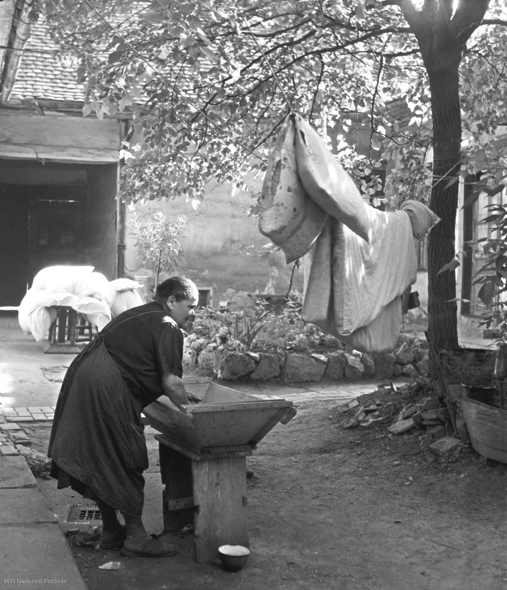 Budapest, 1958. június 3. Egy idős asszony teknőben mos egy régi óbudai ház udvarán.