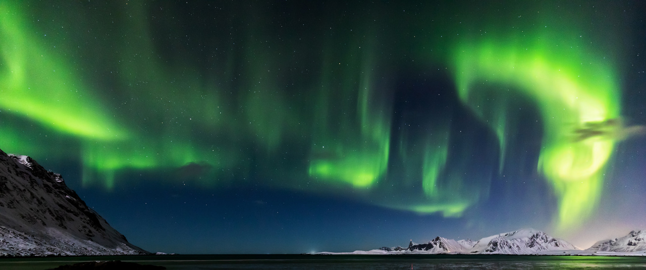 Showtime! Fergeteges látványt nyújt egy kitörés alkalmával az aurora borealis Norvégiában a Lofoten-szigeteken Fredvang település közelében. Ma már viszonylag pontosan jósolható a sarkifény jelenség intenzitása, ennek ellenére kihívás a percenként változó sokszor csak rövid időszakokra felfénylő jelenséget a megörökíteni.