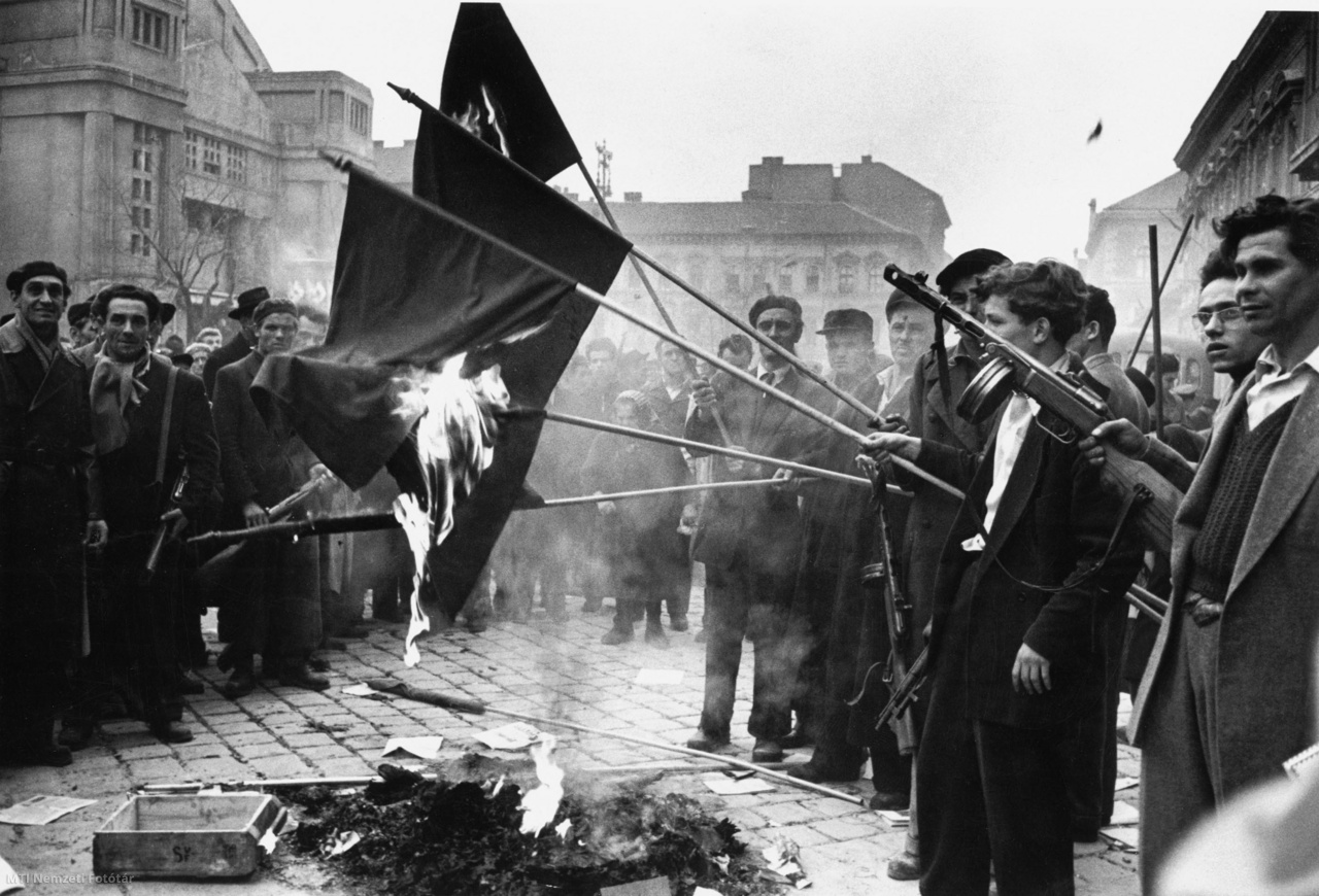 Budapest, 1956. október 30. Fegyveres forradalmárok szovjet zászlókat égetnek a Magyar Dolgozók Pártja (MDP) Köztársaság téri pártháza előtt