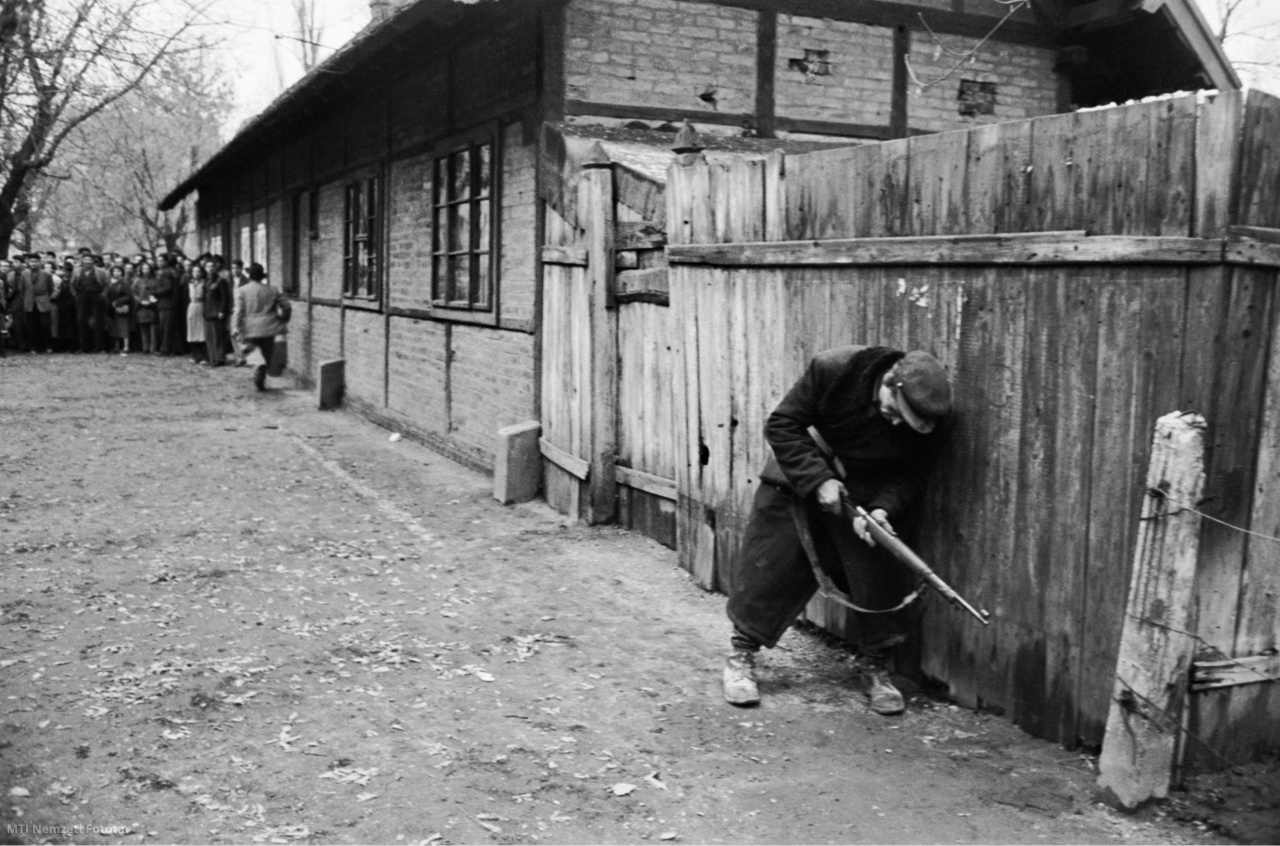 Budapest, 1956. október. Palánkkerítéshez lapulva puskáját tölti újra egy fiatal szabadságharcos. A felvétel készítésének pontos időpontja ismeretlen
