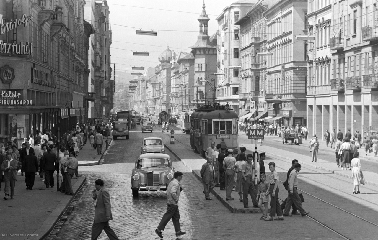 Budapest, 1959. augusztus 8. Járókelők sétálnak és mennek át az úton a személygépkocsik előtt, utasok állnak a villamosmegállóban és "tujázók" utaznak a 68-as villamoson a Rákóczi úton.