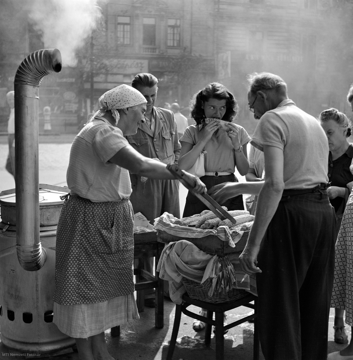 Budapest, 1954. augusztus 5. Nagy a forgalom a főtt kukorica árus asszony pultjánál a budapesti utcán.