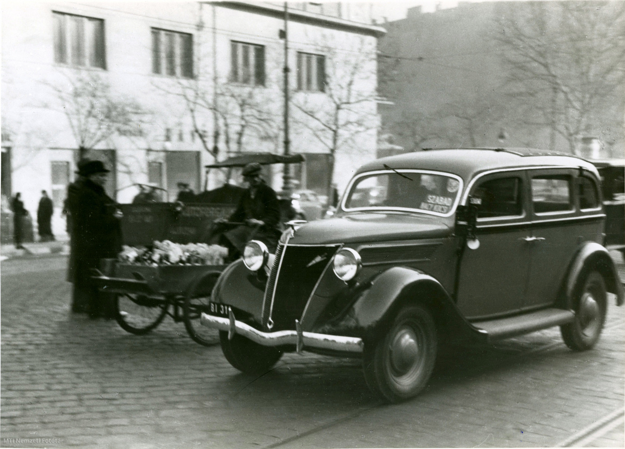 Budapest, 1938. február 1. Szabad jelzésű Ford típusú Szürketaxi és mellette egy tricikli halad a fővárosi utcán. A fotó Kirschner Béla gyűjteményéből származik.