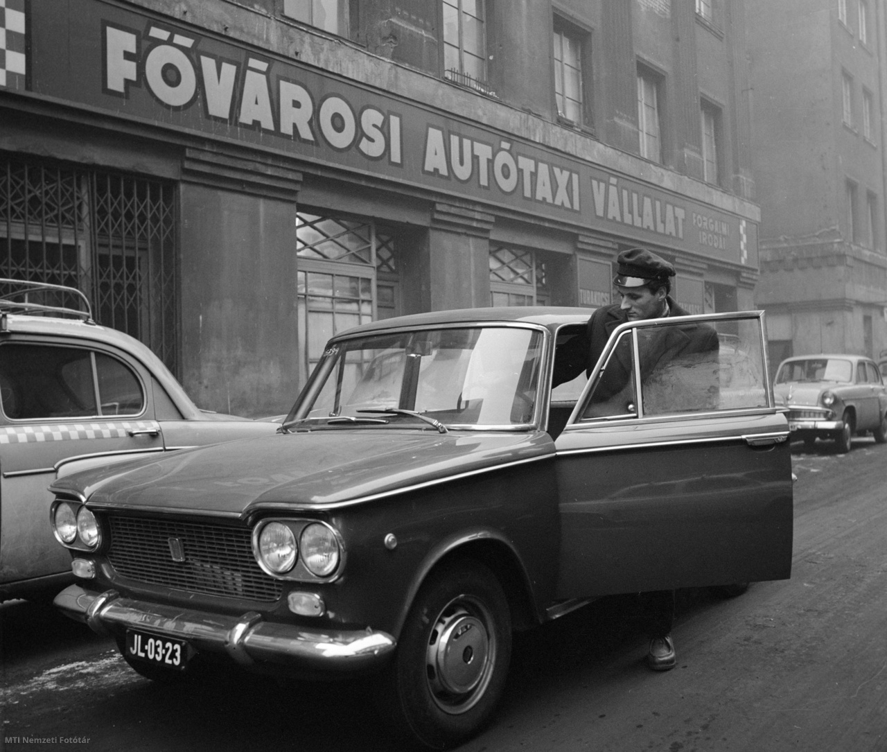 Budapest, 1964. január 20. Az Autótaxi Vállalat sofőrje a bérelhető Fiat 1500-as taxit a megjelölt helyre fuvarozza. Az Autótaxi Vállalat tíz új kocsival, s ezzel új szolgáltatással bővült: a hazánkba érkező külföldiek mától vezető nélkül bérelhetik a gépkocsikat. Autótaxi Vállalat: 1912-ben az aradi Marta Magyar Automobil Rt. elnöke, Haltenberger Samu bérautó vállalatot alapított Budapesten, mely 1913-tól Bp.-i Autótaxi Rt. néven működött. 1948-ban államosították és Autótaxi Nemzeti Vállalat néven összevonták a MOGÜRT-tel. 1951-ben újra önálló lett Fővárosi Autótaxi Vállalat néven. Jogutódja a Főtaxi Zrt.