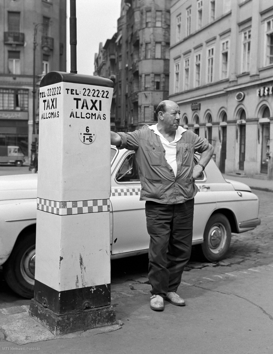Budapest, 1968. augusztus 9. Taxisofőr áll a taxiállomáson, mögötte a taxija.