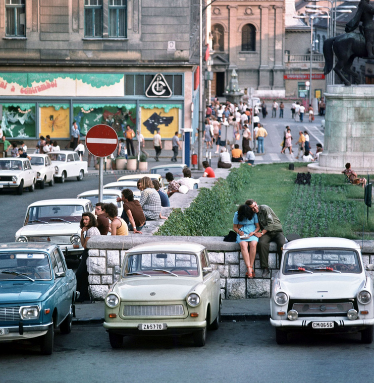 Főként fiatalok beszélgetnek a parkoló autók mellett a Széchenyi téren, Pécsett