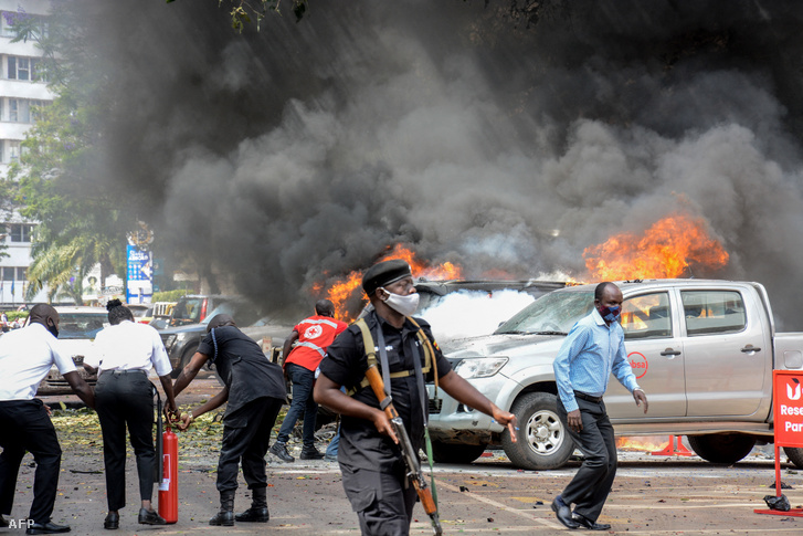 Emberek oltják az autókon keletkezett tüzet, amelyet egy bomba robbanása okozott az ugandai fővárosban, Kampalában 2021. november 16-án