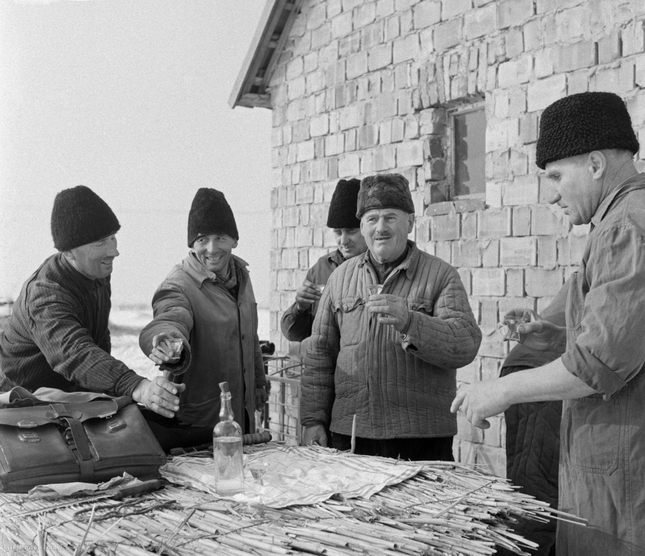 Nagytarcsa, 1966. január 28. Pálinkával koccintanak a nagytarcsai Rákóczi Termelőszövetkezet (Tsz) dolgozói a gazdaság téli disznóvágása előtt.