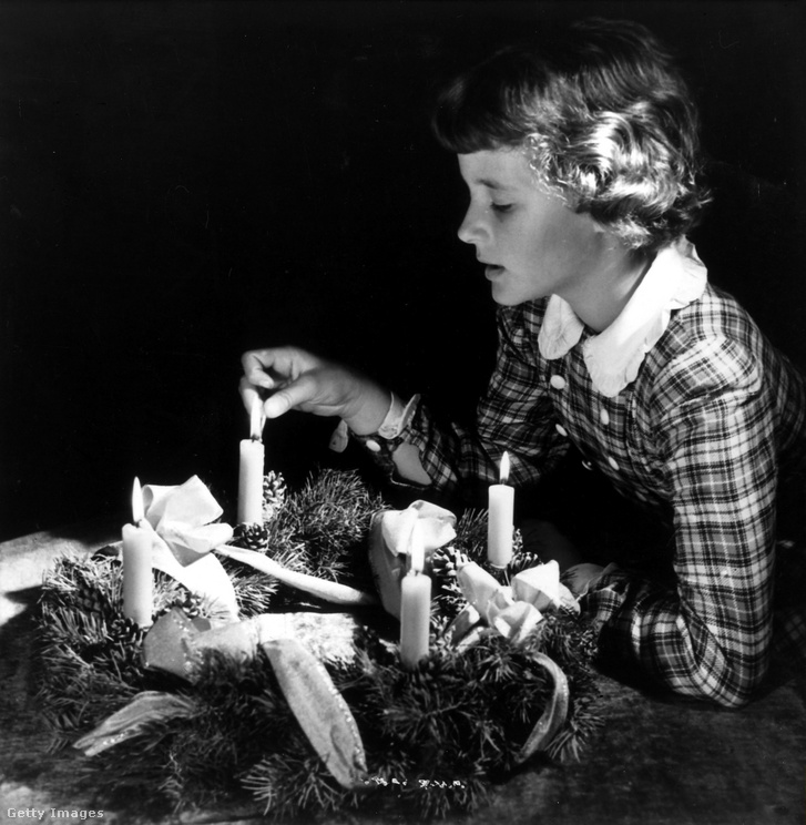 Egy kislány meggyújtja az adventi koszorú gyertyáját Németországban 1950-ben.