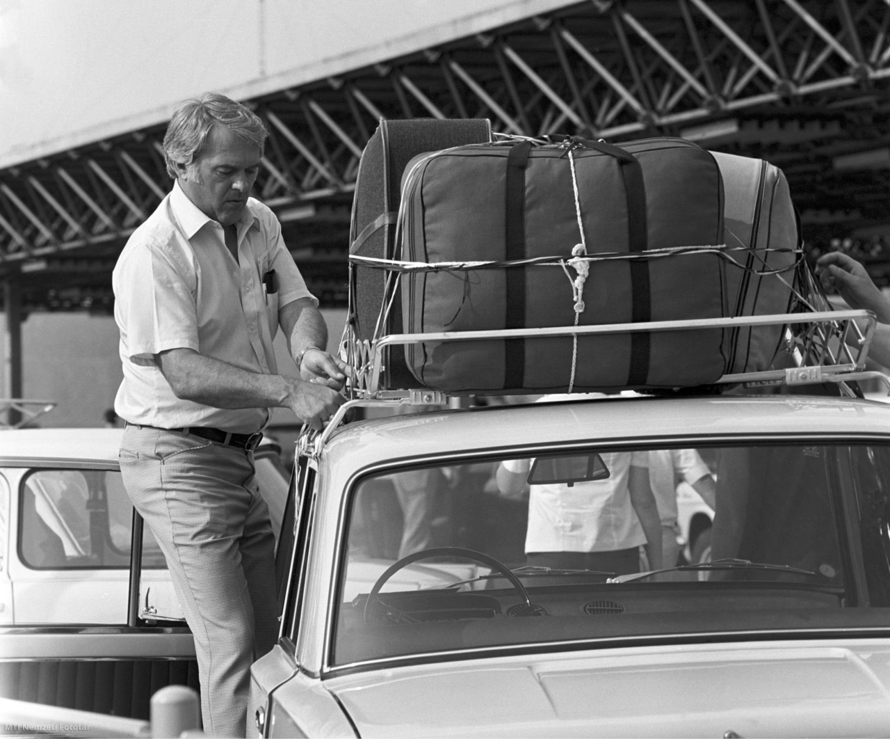 Budapest, 1981. június 23. Egy férfi csomagokat rögzít egy személyautó tetőcsomagtartójára a repülőtér előtt, ahol kölcsönözhető autók várják az utasokat. A Ferihegyi repülőtér tavaly már több, mint egymillió hatszáztizenötezer utast fogadott, s várhatóan ez a szám az idén növekedni fog.