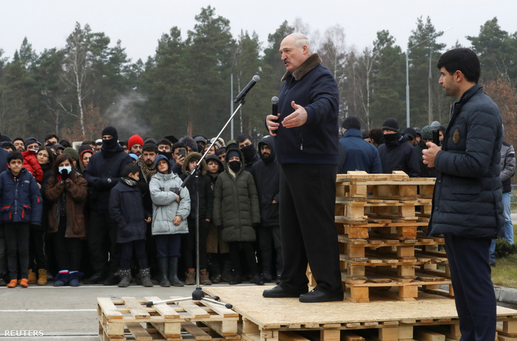 Lukasenka beszél a határon lévő menekülteknek egy raklapokból ácsolt emelvényen 2021. november 26-án
