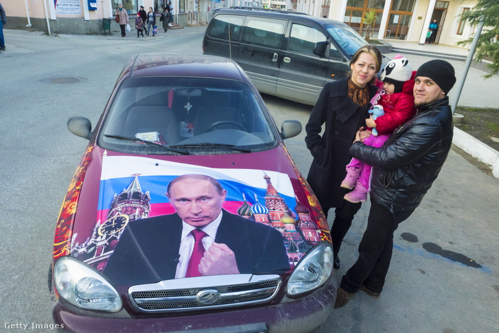 Alla Aman, a Deportált Krími Bolgárok Köztársasági Szövetségének elnökhelyettese lányával és férjével az autójuk mellett állnak, amelyen Vlagyimir Putyin orosz elnök portréja látható, 2016. március 2-án