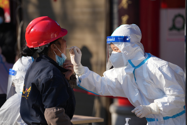 Koronavírus-vizsgálathoz vesz mintát egy pácienstől egy védőruhás egészségügyi dolgozó Hsziánban 2021. december 21-én. December 22-én a hatóságok egy új koronavírusjárvány-góc felbukkanása miatt vesztegzár alá helyezték az északnyugat-kínai Senhszi tartomány 13 millió lakosú székhelyét
