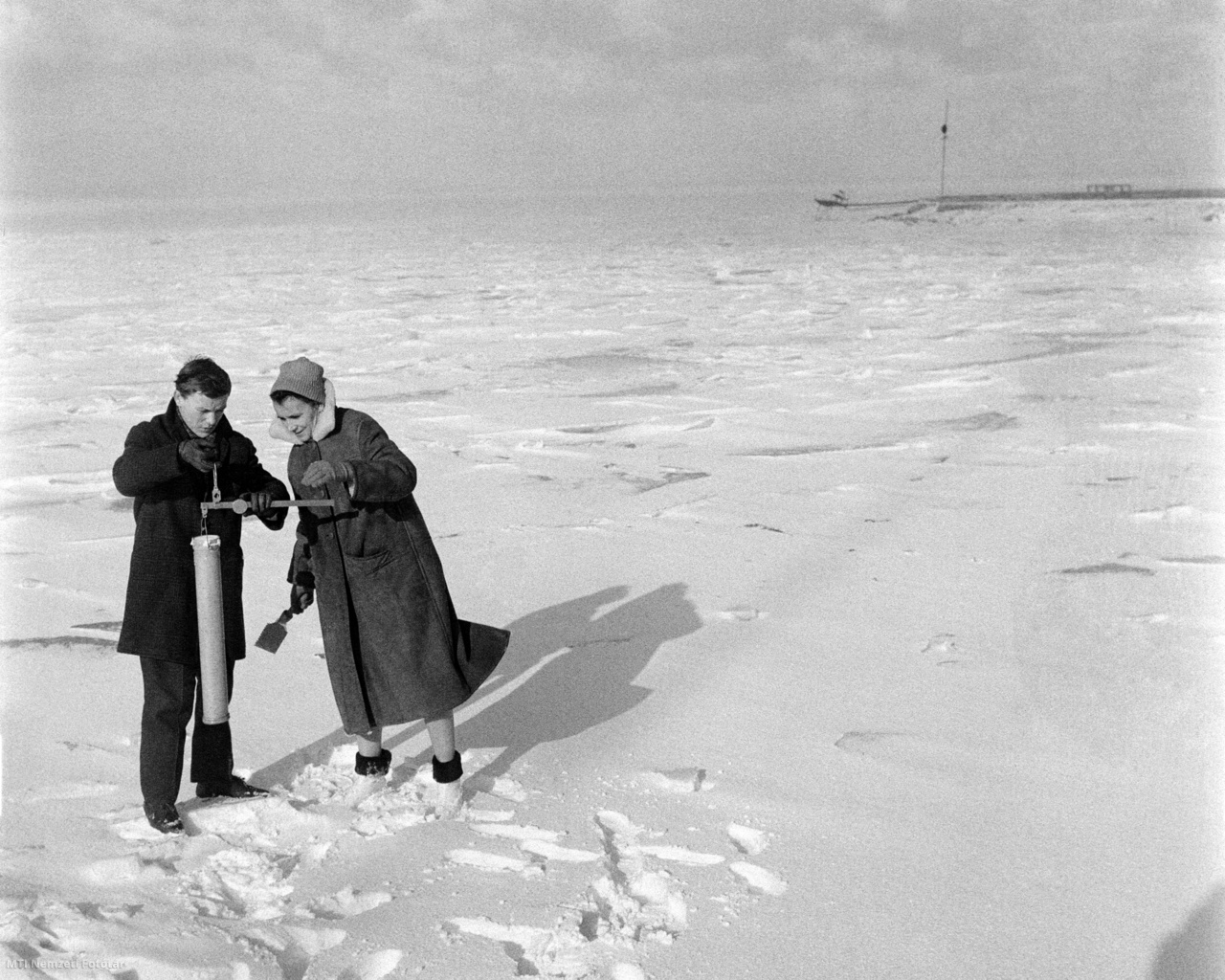 Siófok, 1965. február 9. Az Országos Meteorológiai Intézet siófoki obszervatóriumának munkatársai mintát vesznek a Balaton jegén, hogy méréseket végezhessenek. Vizsgálják a légkör pillanatnyi fizikai állapotát, mérik a levegő hőmérsékletét, nedvességtartalmát, a szél erősségét és a felhőzet fajtáját, a tél adta lehetőségeket kihasználva pedig a hó sűrűségét és a tó jegének vastagságát.