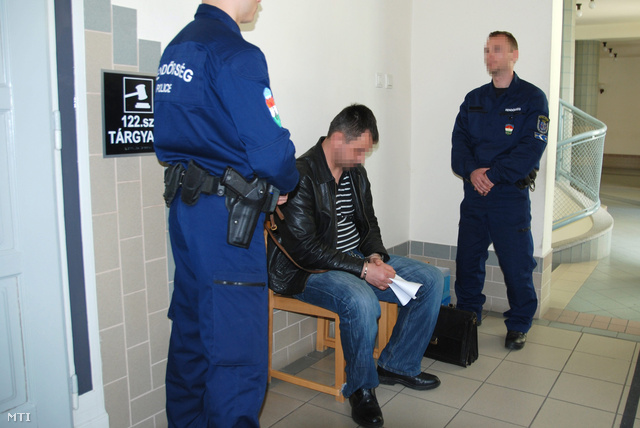 A kényszervallatás és halált okozó testi sértés gyanúja miatt őrizetbe vett két izsáki rendőr egyike várakozik az előzetes letartóztatásról döntő ülés előtt a Kecskeméti Városi Bíróság folyosóján