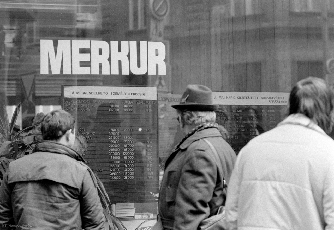 Budapest, 1989. január 9. Járókelők olvassák a Merkur Martinelli téri (1953 előtt és 1992-től Szervita tér) autószalonjának kirakatába kirakott táblát az új árakkal. A Minisztertanács 1989. évi terve alapján január 9-én központi áremeléseket hajtottak végre, így emelkedett egyes gyógyszerek, a mosószerek, valamint a személygépkocsik ára