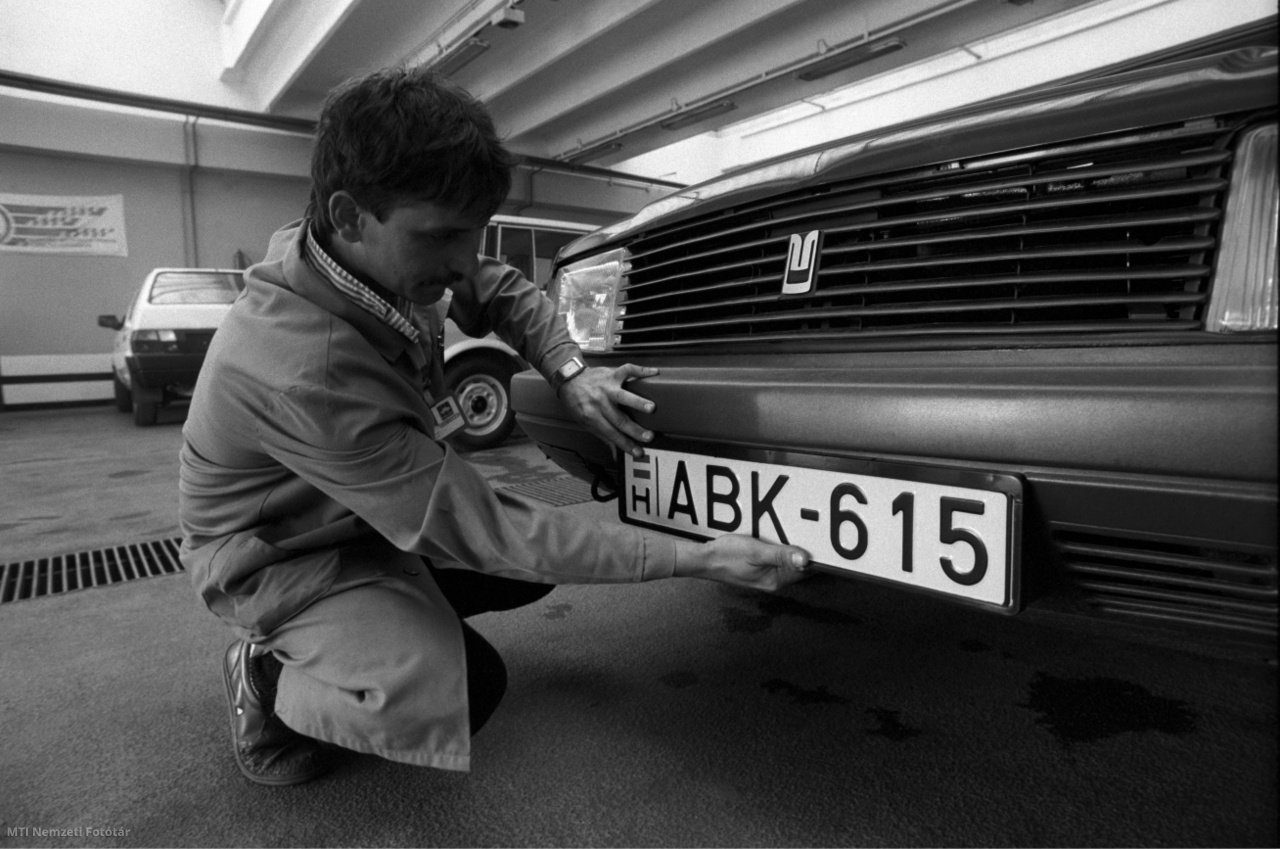 Debrecen, 1990. augusztus 8. Egy szerelő új – 3 betű és 3 szám kombinációjából, valamint a nemzeti trikolórból és az országot jelző H betűből álló – rendszámtáblát tesz egy autóra a Merkur debreceni telepén