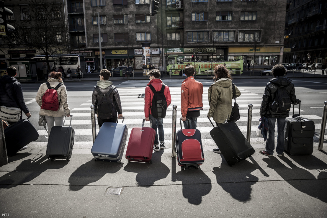 Turisták bőröndjükkel egy zebránál állnak Budapesten, a Rákóczi úton 2014. március 25-én