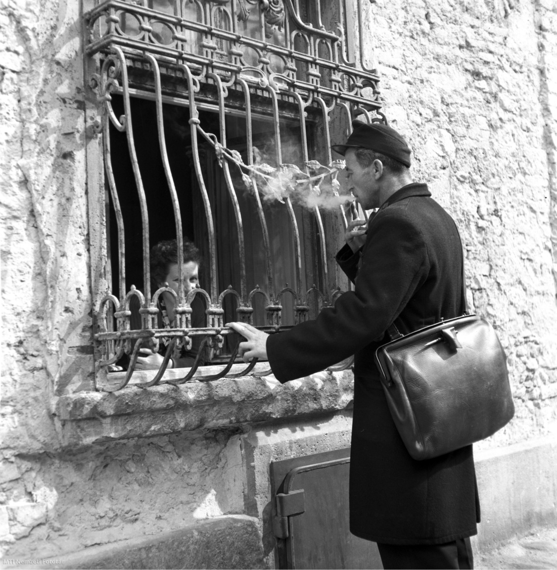 Budapest, 1958. március 11. Egy lakóval beszélget a postás cigarettaszünet közben a Fortuna utcában.