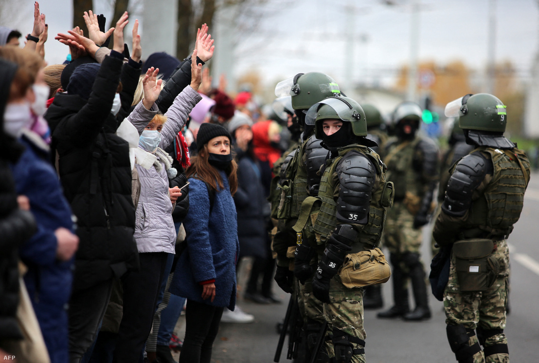 Tüntetők állnak magasba tartott kézzel a készenléti rendőrök egy csoportja előtt Minszkben 2020. november elsején