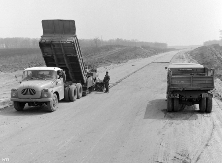 Nagy teherbírású billencses teherautókkal szállítják a stabilizációs rétegként szolgáló betonkeveréket az M1-es autópálya építésénél 1974. május 3-án