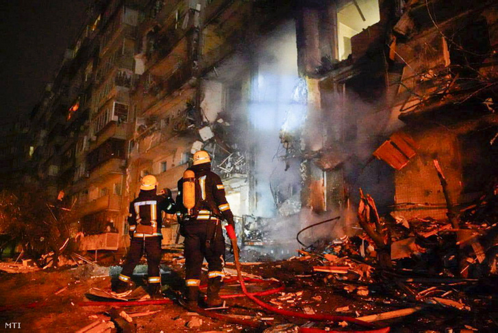 Az ukrán rendőrség sajtószolgálata által közreadott képen tűzoltók vizsgálnak egy rakétatámadás során megrongálódott lakóházat Kijevben 2022. február 25-én