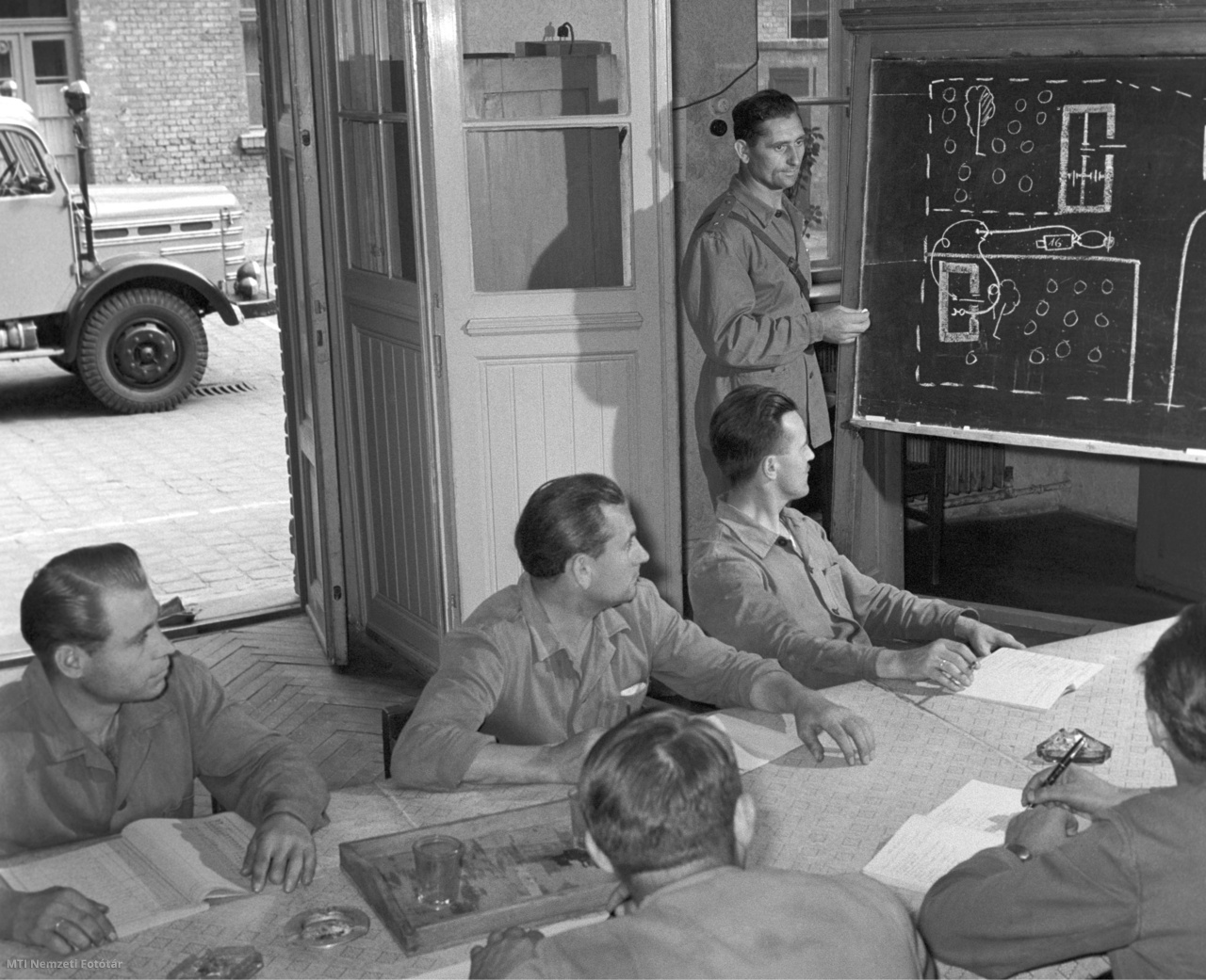 Budapest, 1960. július 8. Tűzoltók ülnek az asztal körül az oktatóteremben, az I. kerületben, ahol Vizi János főhadnagy a fecskendőszerelésről tart előadást, elméleti kiképzés keretében.