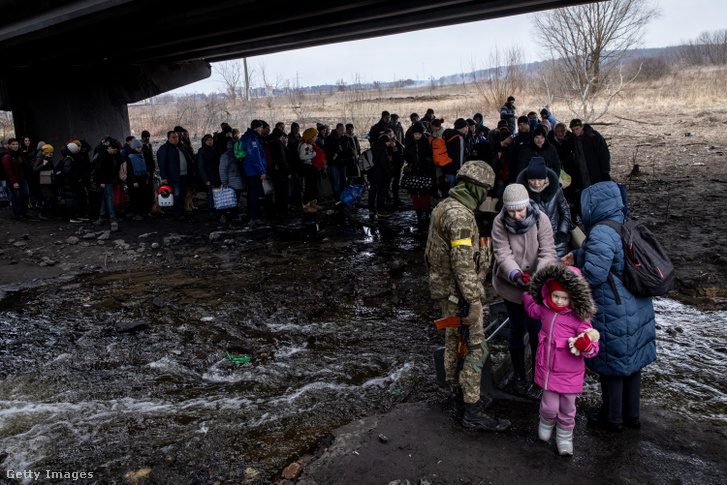 Irpin lakosait evakuálják egy megsemmisült hídon keresztül 2022. március 7-én Ukrajnában