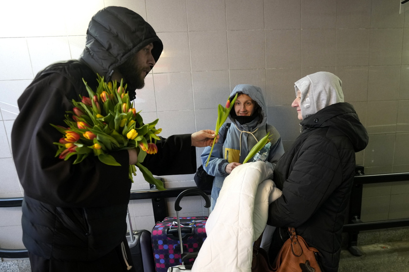 Katolikus pap virágot ad az ukrajnai háború elől menekülő nőknek a nemzetközi nőnap alkalmából a lengyel-ukrán határ lengyel oldalán lévő Przemysl pályaudvarán.