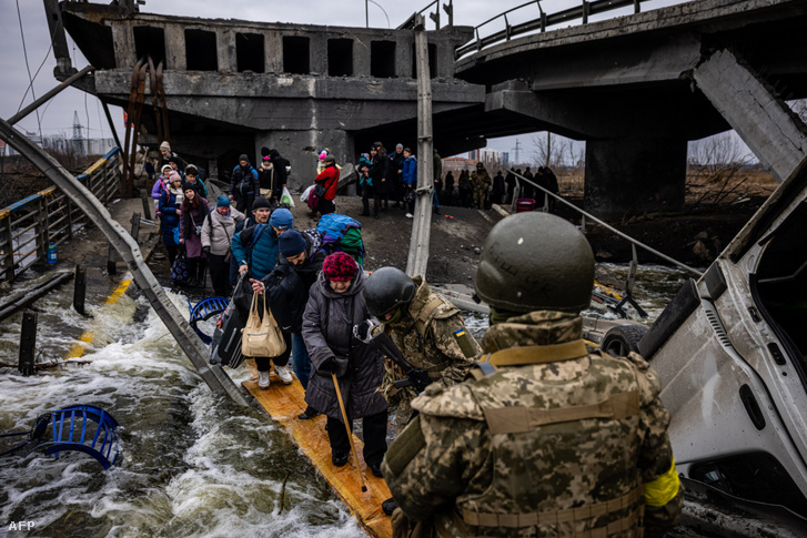 Ukrán emberek egy megrongálódott híd alatt hagyják el Irpint, Kijev egyik peremkerületét 2022. március 7-én