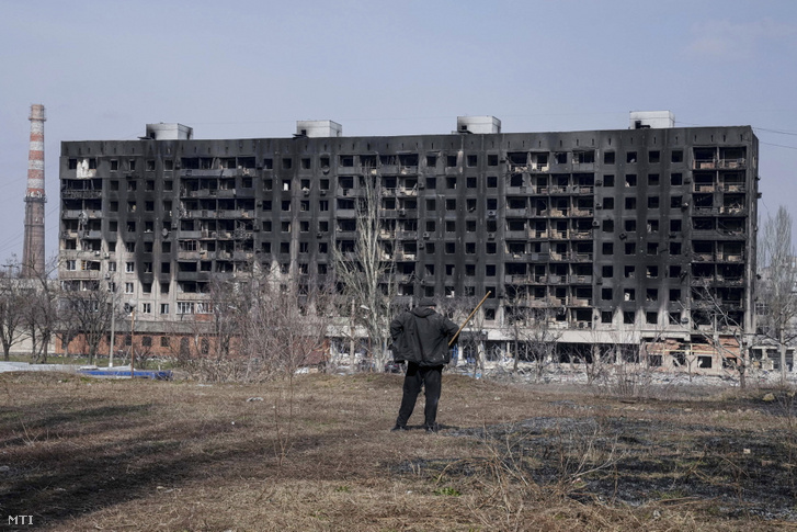 Tüzérségi támadásban megrongálódott lakóházat néz egy férfi Mariupolban 2022. március 13-án