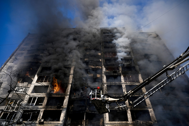 Tűzoltók egy darun állva oltják a tüzet egy lakóháznál Kijevben 2022. március 15-én