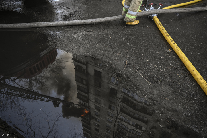 Tűzoltók dolgoznak egy tüzérségi támadásban megrongálódott lakóháznál Kijevben 2022. március 15-én