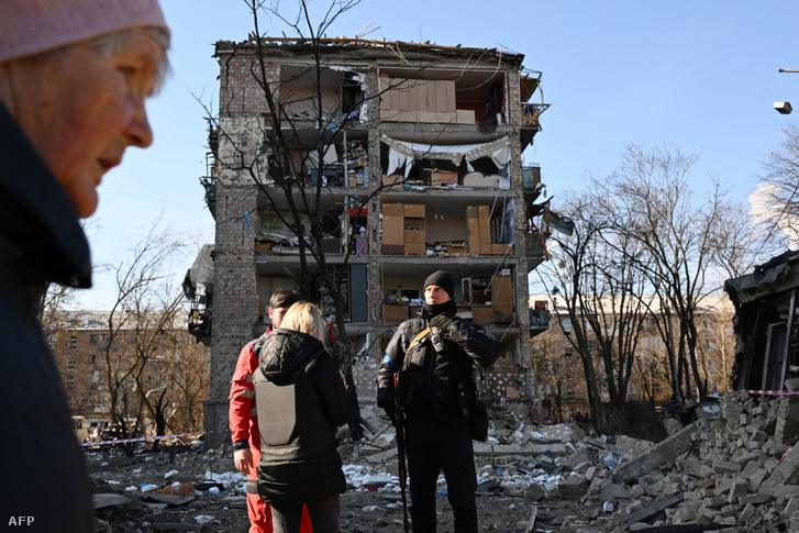 Egy ukrán rendőr biztosítja a területet egy bombatámadásban megrongálódott lakóépület előtt Kijevben 2022. március 18-án