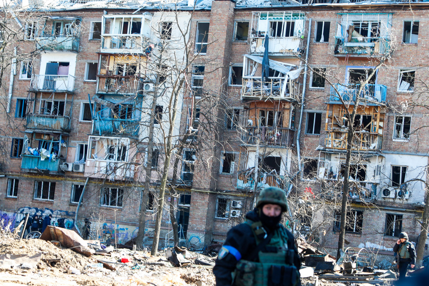Egy ukrán katona elhalad a romok között egy szétlőtt lakóépület mellett.