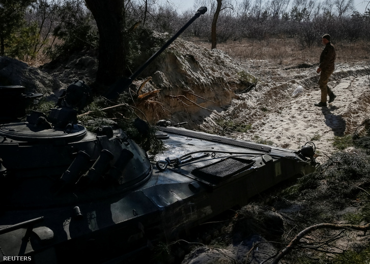 Ukrán katona egy gyalogsági harcjármű közelében az észak-kijevi régióban lévő frontvonalban 2022. március 18-án