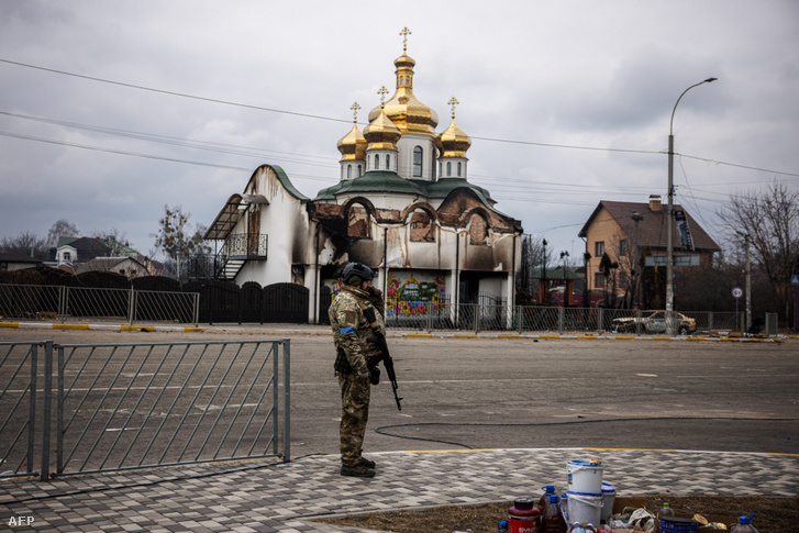 Egy ukrán katona áll egy megrongálódott templom előtt Irpin városában, Ukrajnában 2022. március 13-án