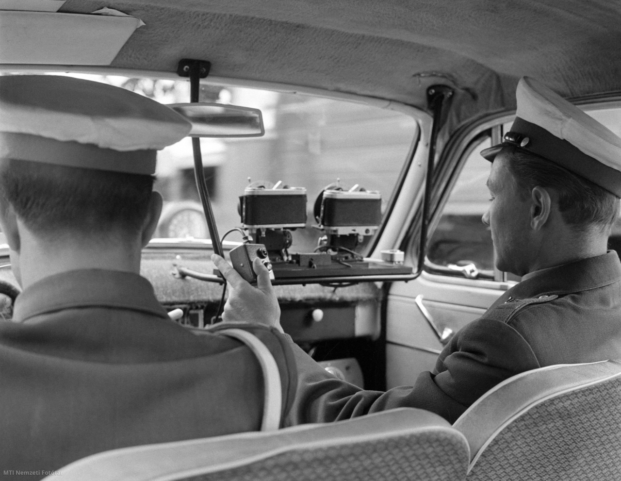 Budapest, 1965. augusztus 27. Rendőrautóba szerelt, fényképezőgépekkel kombinált közúti sebességmérő műszert (traffipax) kezel egy rendőr. A Közlekedésrendészet közúti ellenőrző csoportja újfajta technikai felszerelést használ a közúti közlekedés ellenőrzésénél. A berendezés fényképeken regisztrálja a gyorshajtást.