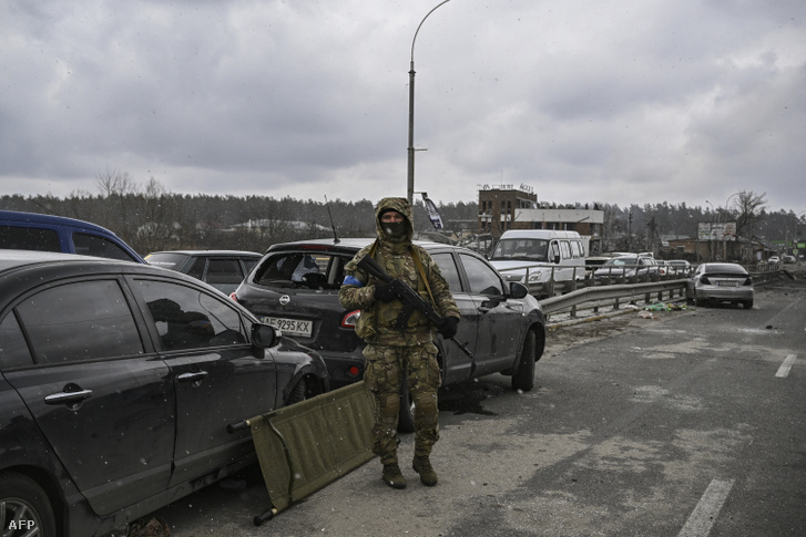 Egy ukrán katona áll egy lerombolt hídon Irpin városában 2022. március 13-án