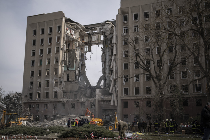 Ukrán katonák és tűzoltók az orosz légitámadásban megsemmisült helyi kormányépület romjai előtt 2022. március 29-én