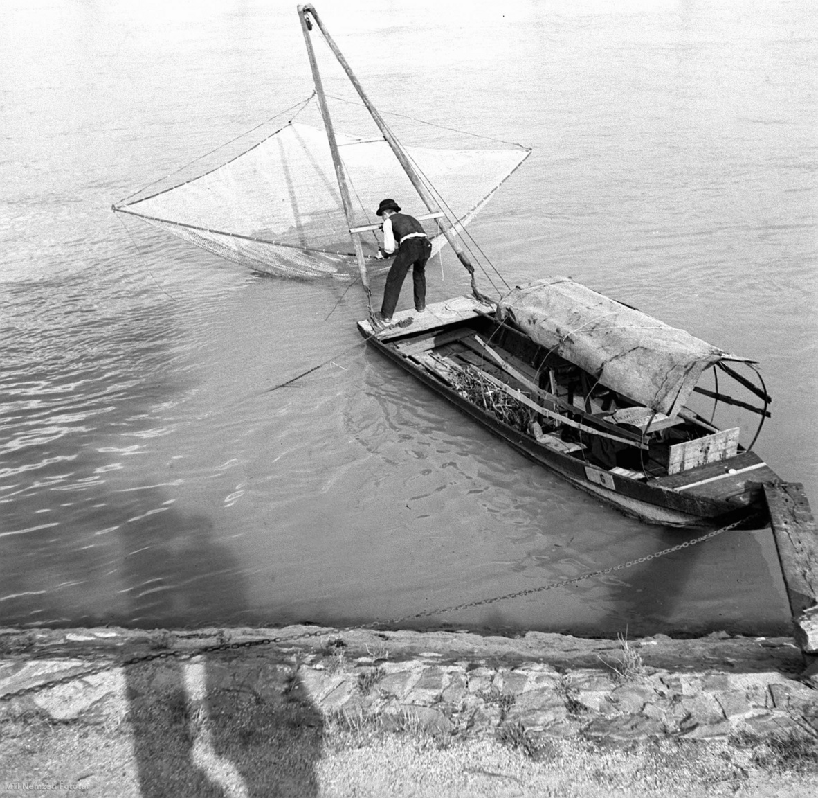 Magyarország, 1930-as évek  Halász a vízbe meríti hálóját. A felvétel készítésének pontos dátuma és helyszíne ismeretlen.