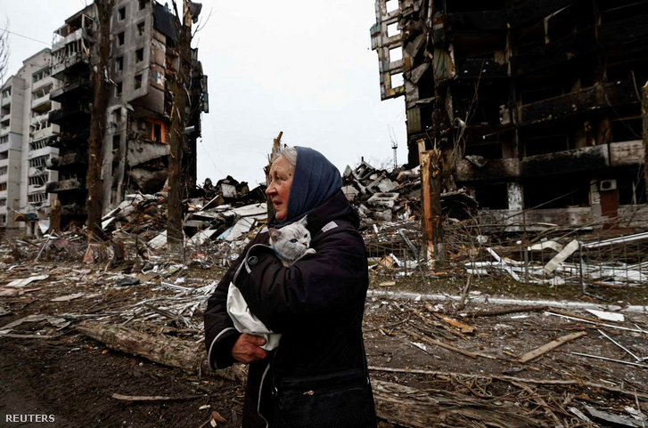 Egy nő a macskájával egy lerombolt épület mellett a Kijevi régióban Ukrajnában, 2022. április 5-én