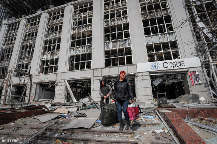 Helyi lakosok hordják holmijukat egy megsemmisült épület közelében, Mariupolban Ukrajna déli kikötővárosában 2022. április 10-én