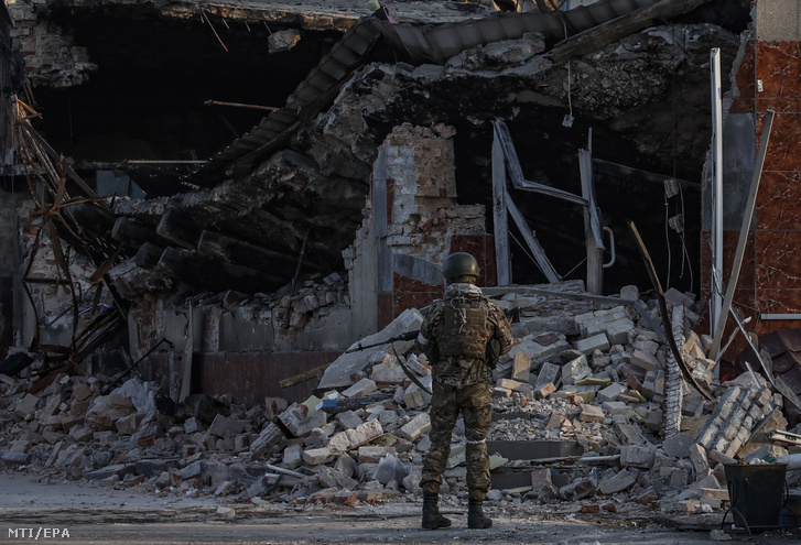 Orosz katona egy lerombolt áruház romjait nézi a Donyeck megye déli részén fekvő Volnovahában 2022. március 26-án