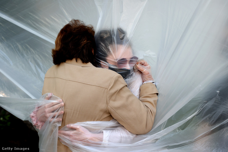 Olivia Grant átöleli nagymamáját, Mary Grace Sileót egy műanyag zsákon keresztül a koronavírus okozta közösségi távolságtartás miatt 2020. május 24-én