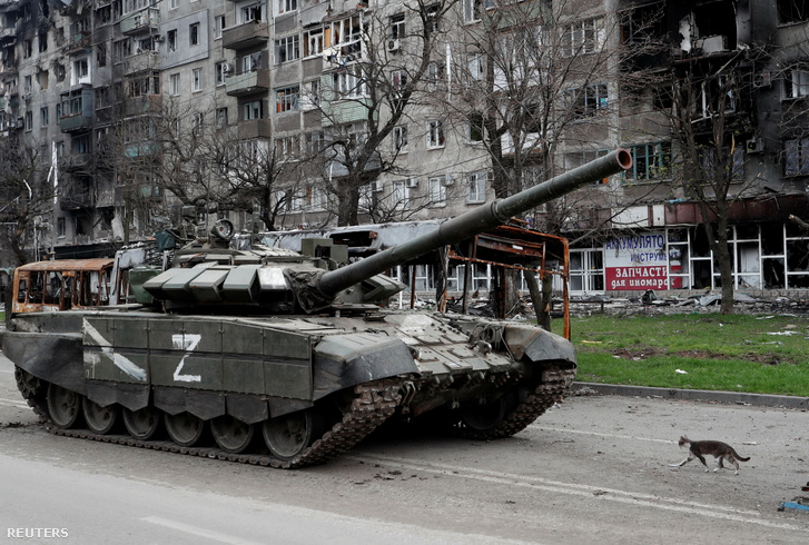 Orosz tank halad el megsérült bérház előtt Mariupolban, Ukrajna déli kikötővárosában, 2022. április 19-én