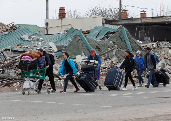 Helyi lakosok egy lerombolt épület mellett haladnak el Mariupolban Ukrajnában 2022. április 19-én
