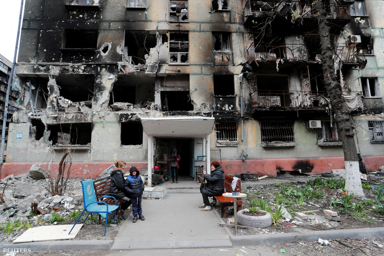 A harcok szünetében egy lerombolt épület tövében várakozó civilek.