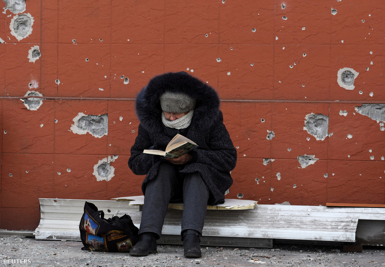 Egy helybéli könyvet olvas egy lakhatatlanná vált épület előtt.